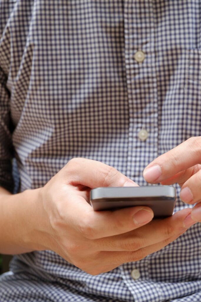 Close-up of a man using a smartphone, focusing on hands and modern technology.